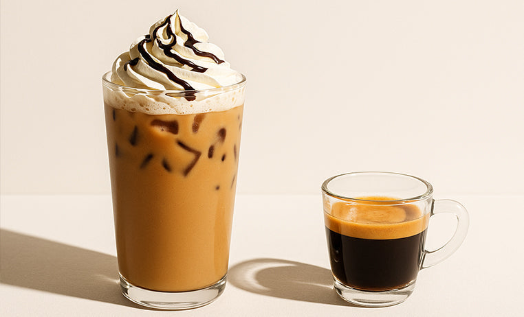 two cups of coffee, on the left one with lots of sugar, whipped cream, chocolate and ice. On the left a single cup of espresso.