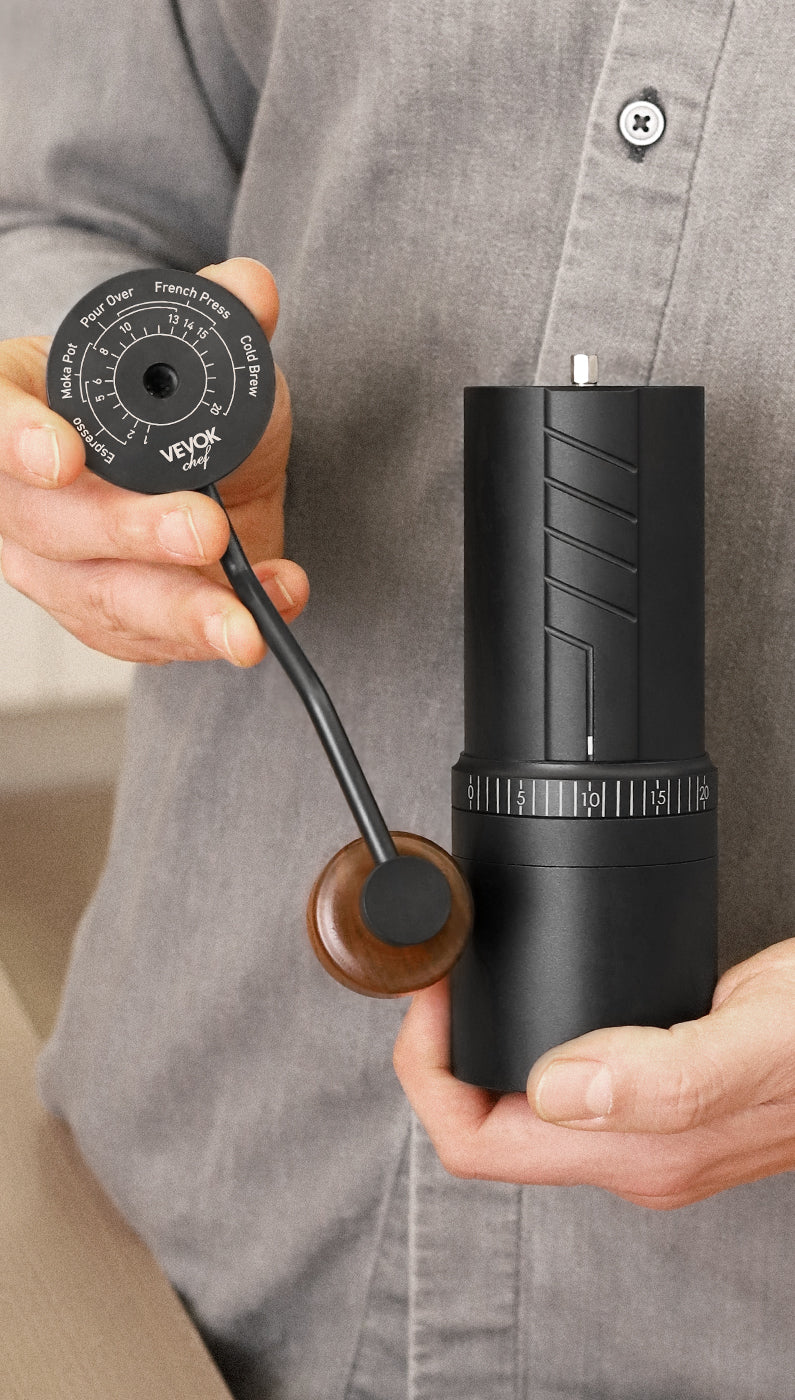 A person holding the VEVOK CHEF O20 Manual Coffee Grinder with one hand while showing the coarseness guide inside the lid, emphasizing its user-friendly design.