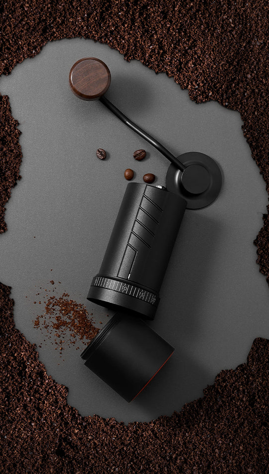 Top-down view of the VEVOK CHEF O20 Manual Coffee Grinder surrounded by coffee grounds, with the lid and grounds container open, highlighting its precision and ease of use during grinding.