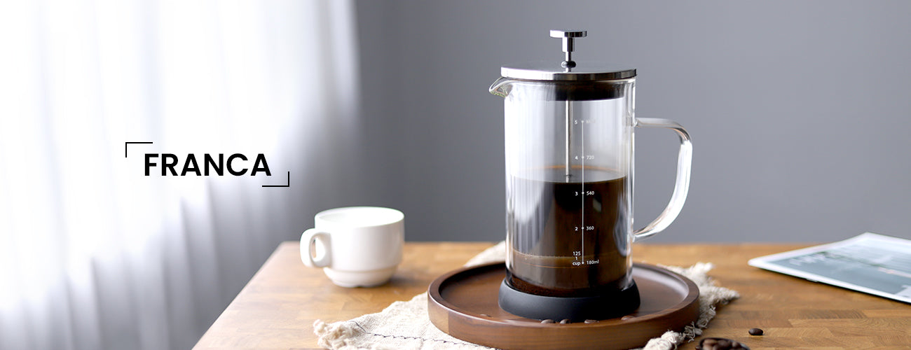 French press with coffee on a wooden table, featuring the brand 'Franca'.