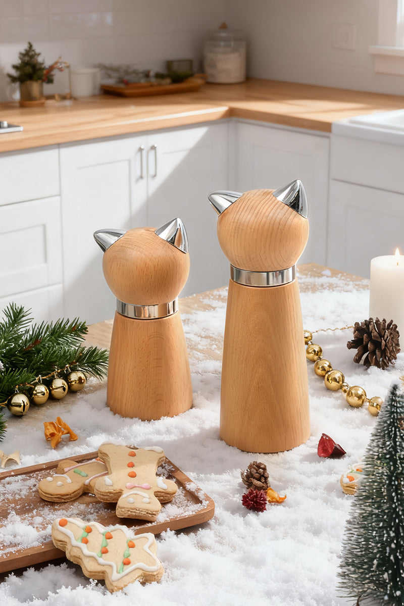 Wooden cat-shaped salt and pepper shakers on a kitchen counter with Christmas decorations.